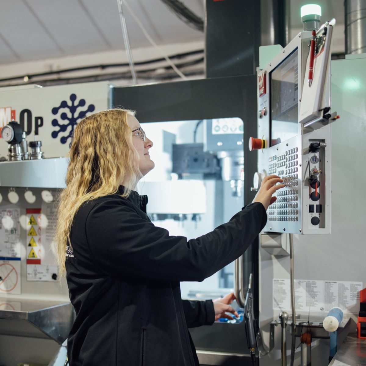 Battery technician Siobhan, using a screen to programme a large industrial CNC machine.